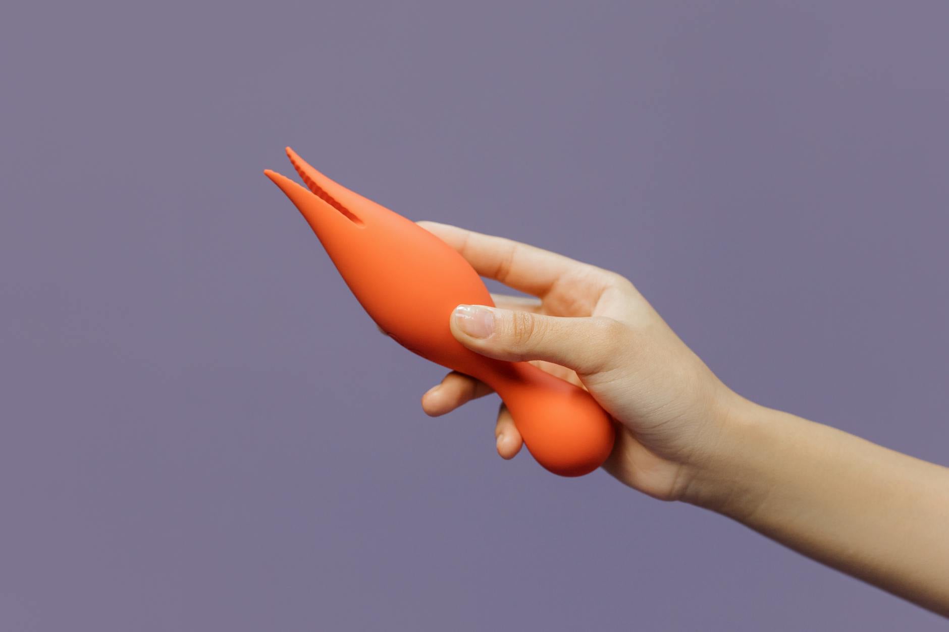 A hand holding a lemon vibrator against a minimalist purple backdrop, symbolizing gentle reconnection and sensual healing.