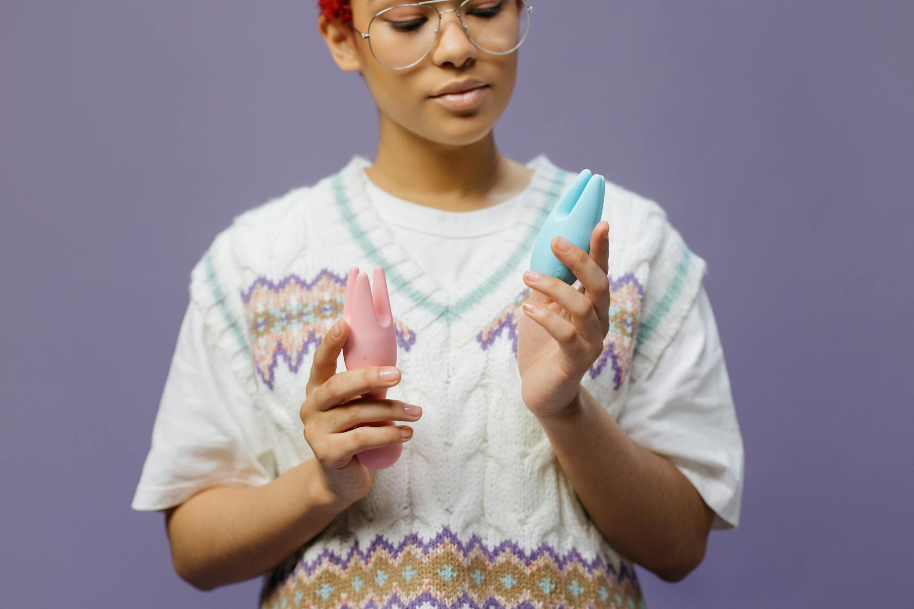 Woman holding colorful vibrators thoughtfully, considering intimacy after a break from sex