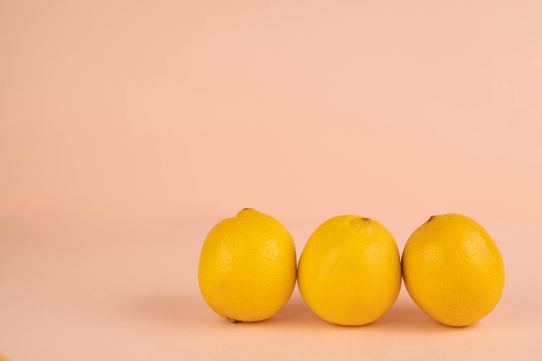 Hand holding a fresh lemon on soft pink background, symbol of intimate health and renewal