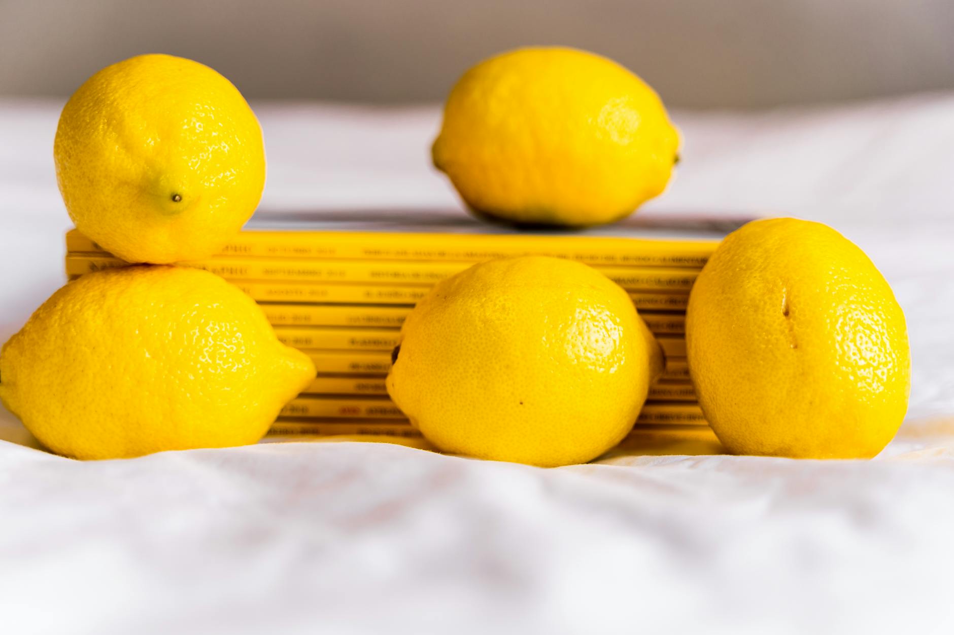 Fresh whole lemons arranged with books on white tablecloth, symbolizing renewal and rediscovery